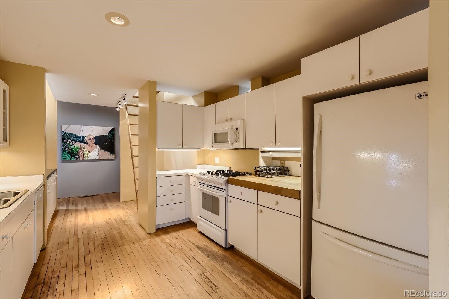 3349 Blake Street Denver, CO 80205 - Photo 18 of 28 a kitchen with stainless steel appliances granite countertop a refrigerator a stove and white cabinets with wooden floor