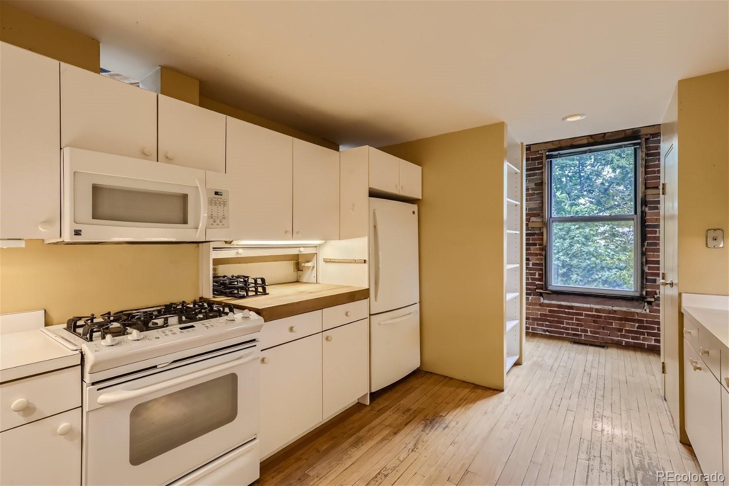 3349 Blake Street Denver, CO 80205 - Photo 19 of 28 a kitchen with granite countertop a stove a sink and a microwave