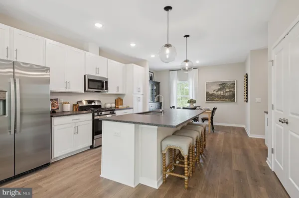 a kitchen with kitchen island a white counter top space stainless steel appliances and cabinets