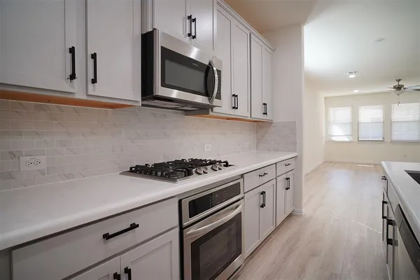 an empty room with wooden floor chandelier fan and windows