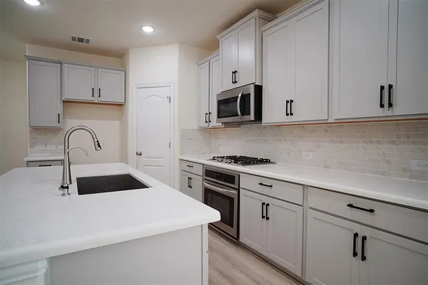 a kitchen with white cabinets and stainless steel appliances