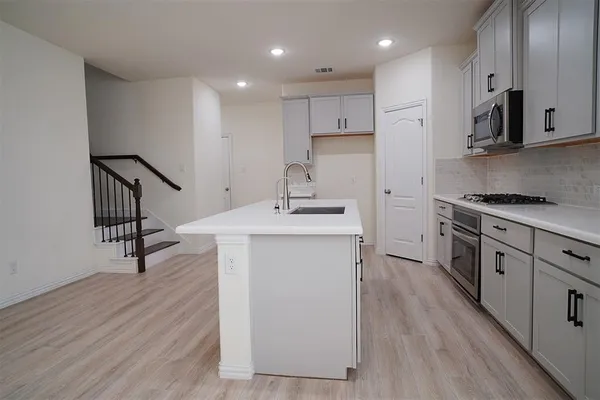 a kitchen with stainless steel appliances white cabinets and a stove top oven