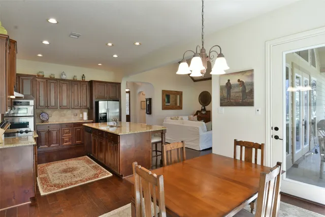 a kitchen with stainless steel appliances kitchen island granite countertop a table chairs and a refrigerator
