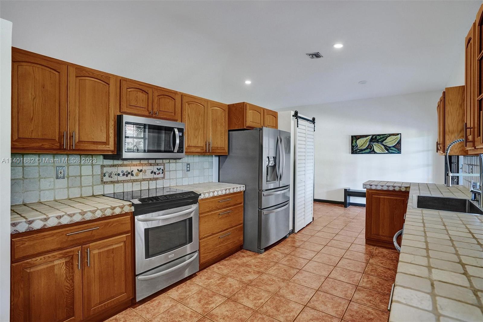 15971 Southwest 252nd Street Homestead, FL 33031 - Photo 23 of 92 a kitchen with stainless steel appliances granite countertop a stove a sink dishwasher a refrigerator and a microwave
