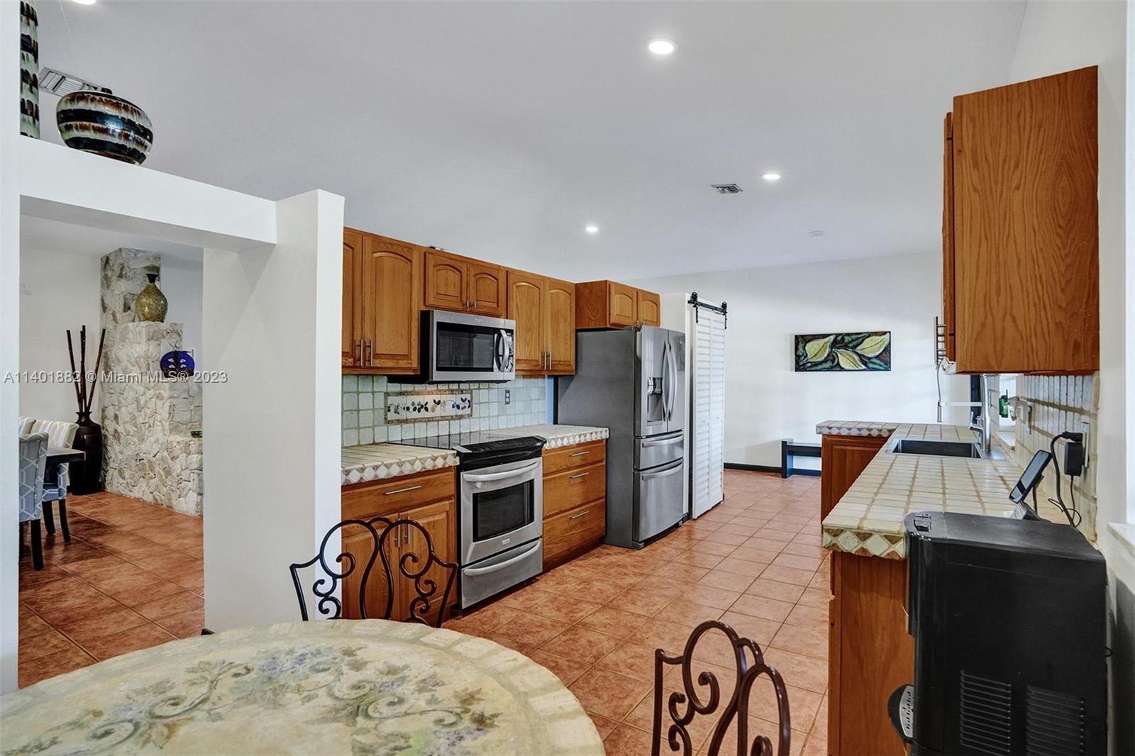 15971 Southwest 252nd Street Homestead, FL 33031 - Photo 24 of 92 a kitchen with stainless steel appliances granite countertop a stove top oven a sink a dining table and chairs with wooden floor