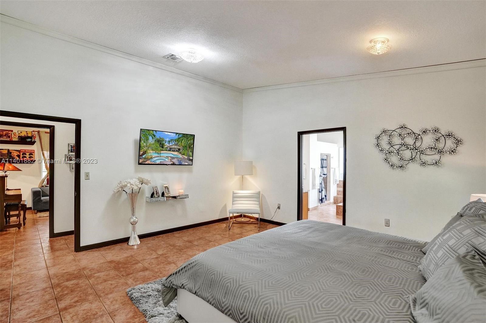 15971 Southwest 252nd Street Homestead, FL 33031 - Photo 47 of 92 a bedroom with a large bed and a chandelier