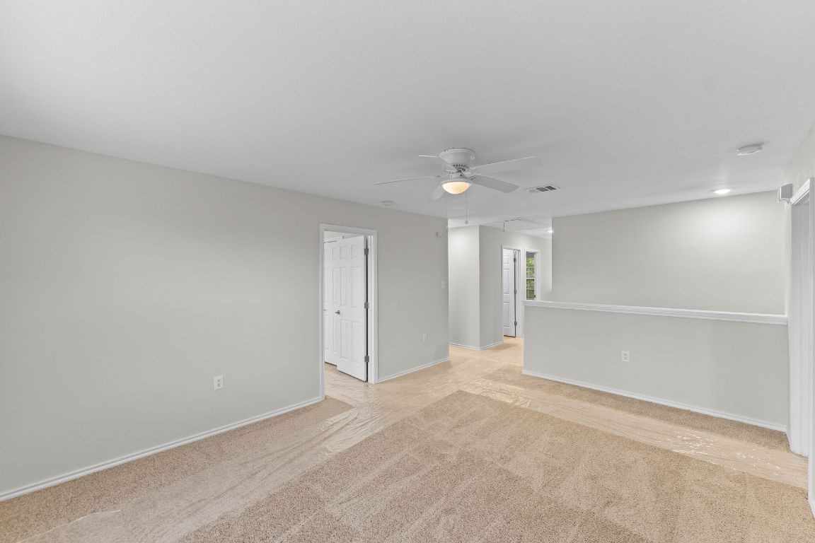 292 Housefinch Loop Leander, TX 78641 - Photo 13 of 29 Empty room featuring light carpet and a ceiling fan