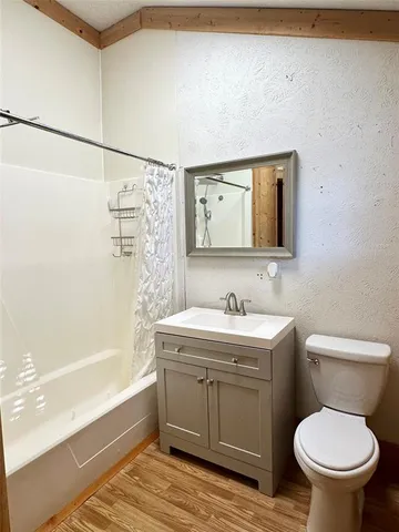 an empty room with wooden floor and fan
