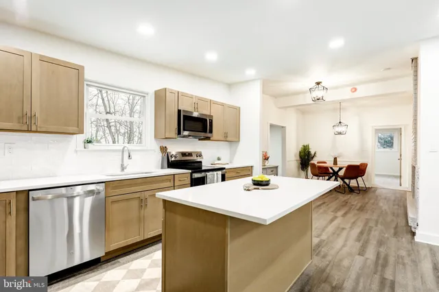 a large white kitchen with a sink dishwasher stove and wooden cabinets