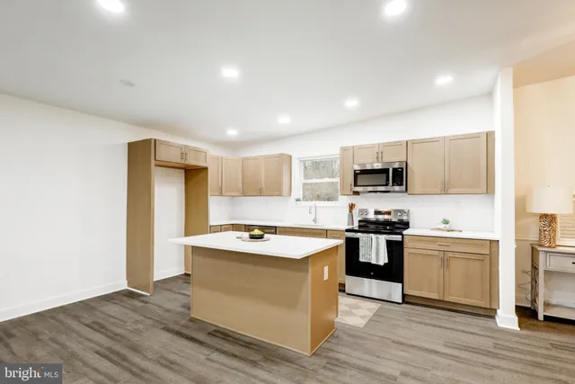 a kitchen with stainless steel appliances granite countertop a stove top oven a sink dishwasher and a refrigerator with wooden floor