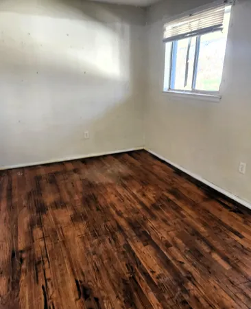 en empty room with wooden floor and windows