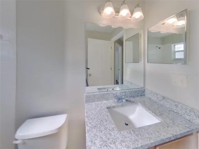 a bathroom with a granite countertop sink a toilet and a large mirror