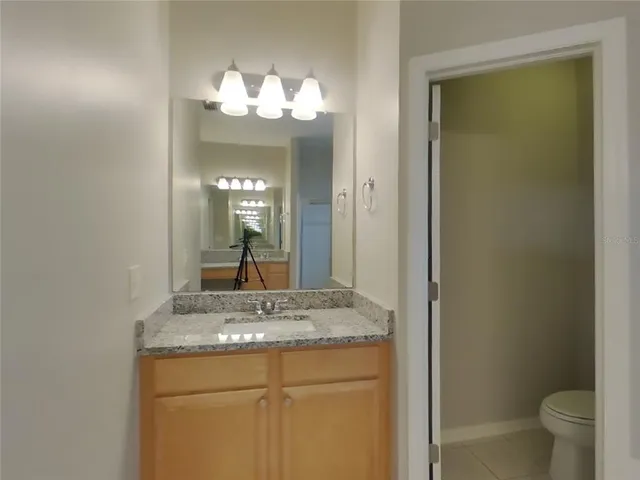 a bathroom with a granite countertop sink a toilet and a mirror