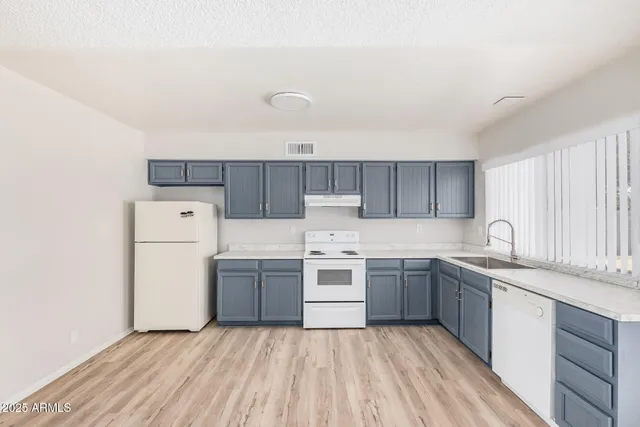 a kitchen with a sink a stove top oven and white stainless steel appliances