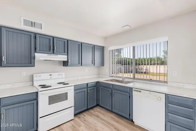 a kitchen with a white stove top oven sink and cabinets