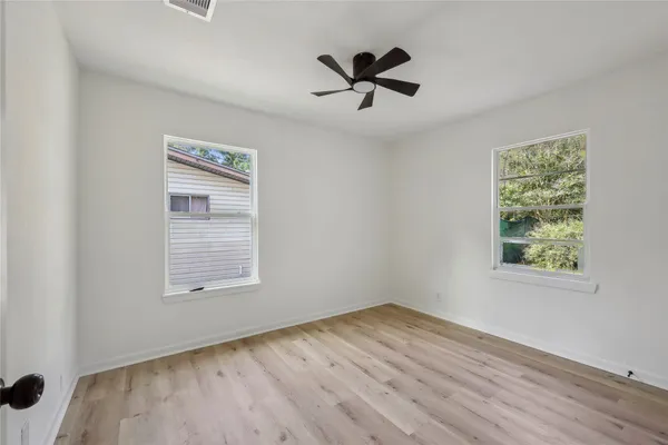 a view of empty room with wooden floor and fan