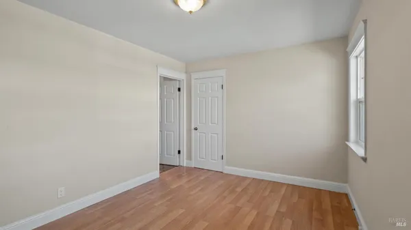a view of an empty room with wooden floor and closet