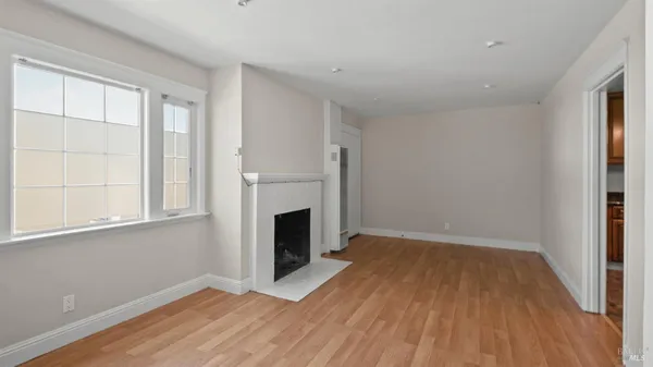 a view of empty room with wooden floor and fireplace