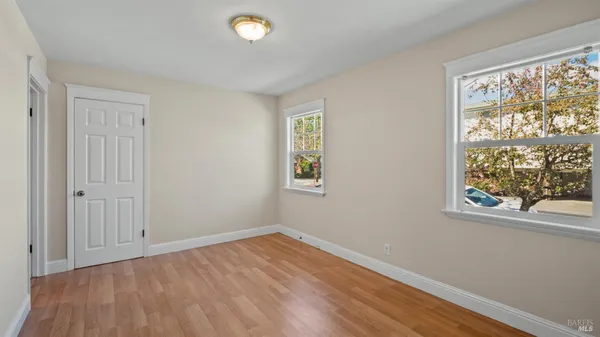 a view of empty room with wooden floor and fan