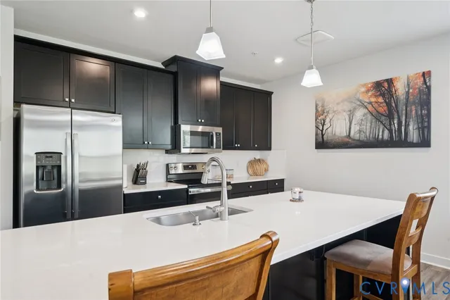 a kitchen with stainless steel appliances kitchen island granite countertop a refrigerator a sink a stove a dining table and chairs