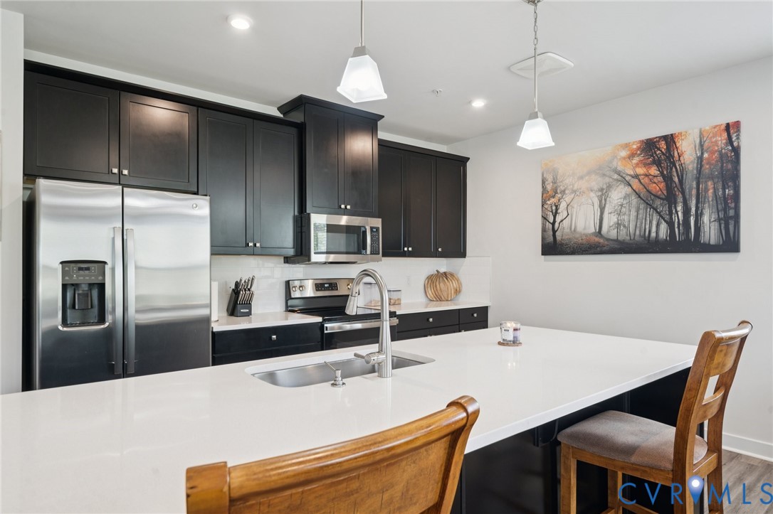 4000 Maze Runner Drive, Unit 103 Midlothian, VA 23112 - Photo 5 of 24 a kitchen with stainless steel appliances kitchen island granite countertop a refrigerator a sink a stove a dining table and chairs