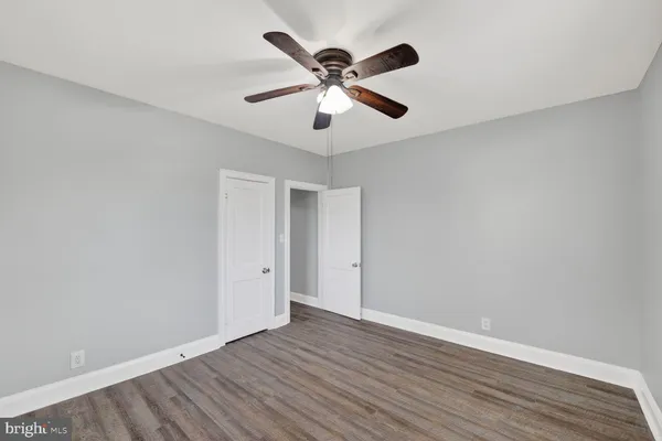an empty room with wooden floor and ceiling fan