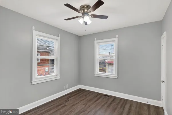a view of an empty room with window and wooden floor