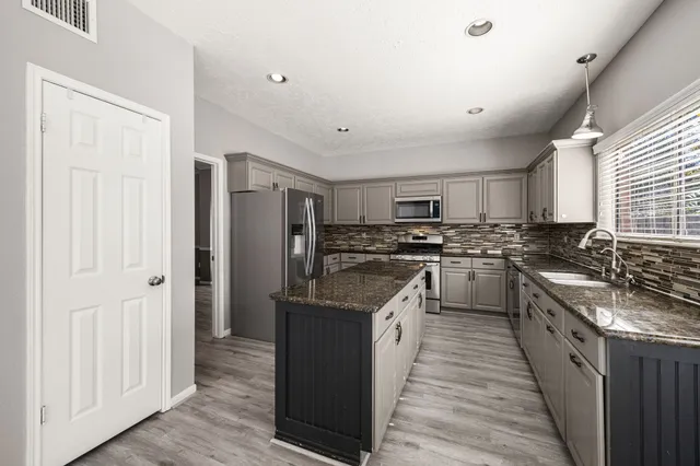 a kitchen with stainless steel appliances granite countertop a stove top oven a sink and a refrigerator