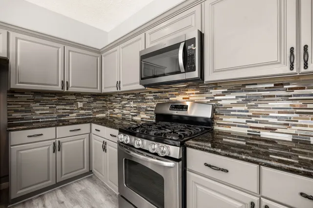 a kitchen with granite countertop white cabinets stainless steel appliances and a sink