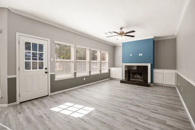 an empty room with windows a fireplace and wooden floor