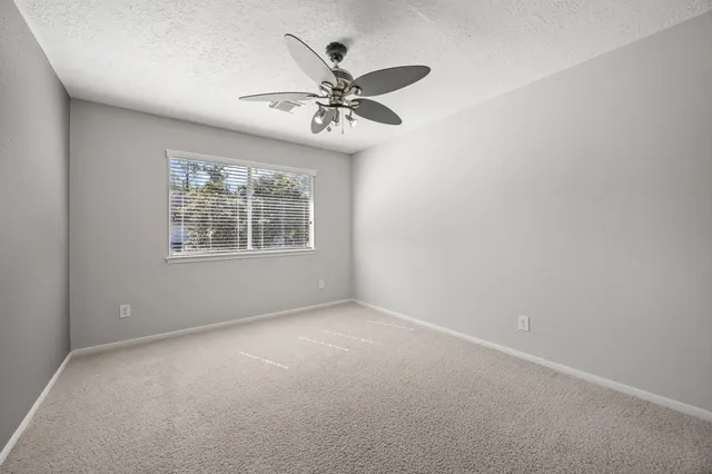 an empty room with windows and fan