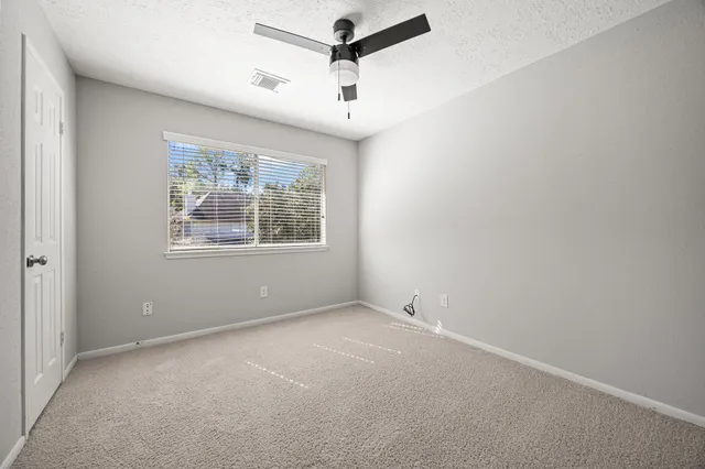 an empty room with windows and fan