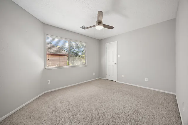 an empty room with windows and ceiling fan