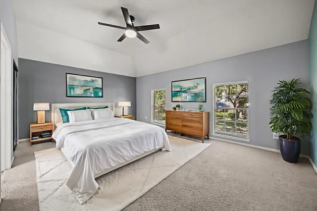 a spacious bedroom with a bed a couch and a ceiling fan