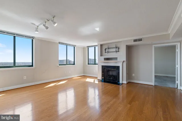 a view of a livingroom with a fireplace a ceiling fan and windows