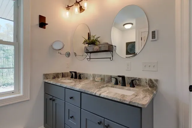 a bathroom with a granite countertop sink a mirror and shower