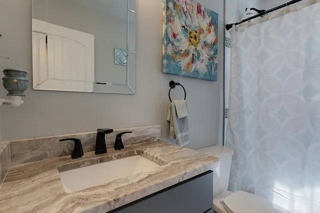 a bathroom with a granite countertop sink vanity mirror and toilet