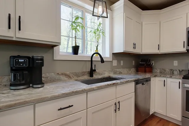 a kitchen with stainless steel appliances granite countertop a sink window and cabinets