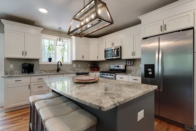 a kitchen with stainless steel appliances granite countertop a sink a refrigerator and microwave