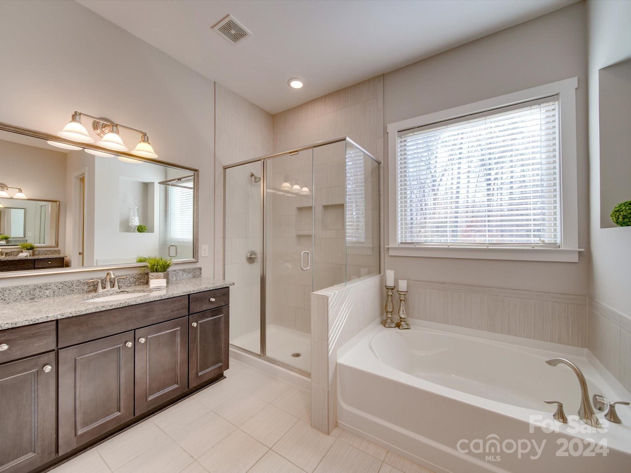 6723 Eliah Drive Weddington, NC 28104 - Photo 22 of 48 a bathroom with a tub a sink a mirror a shower and window