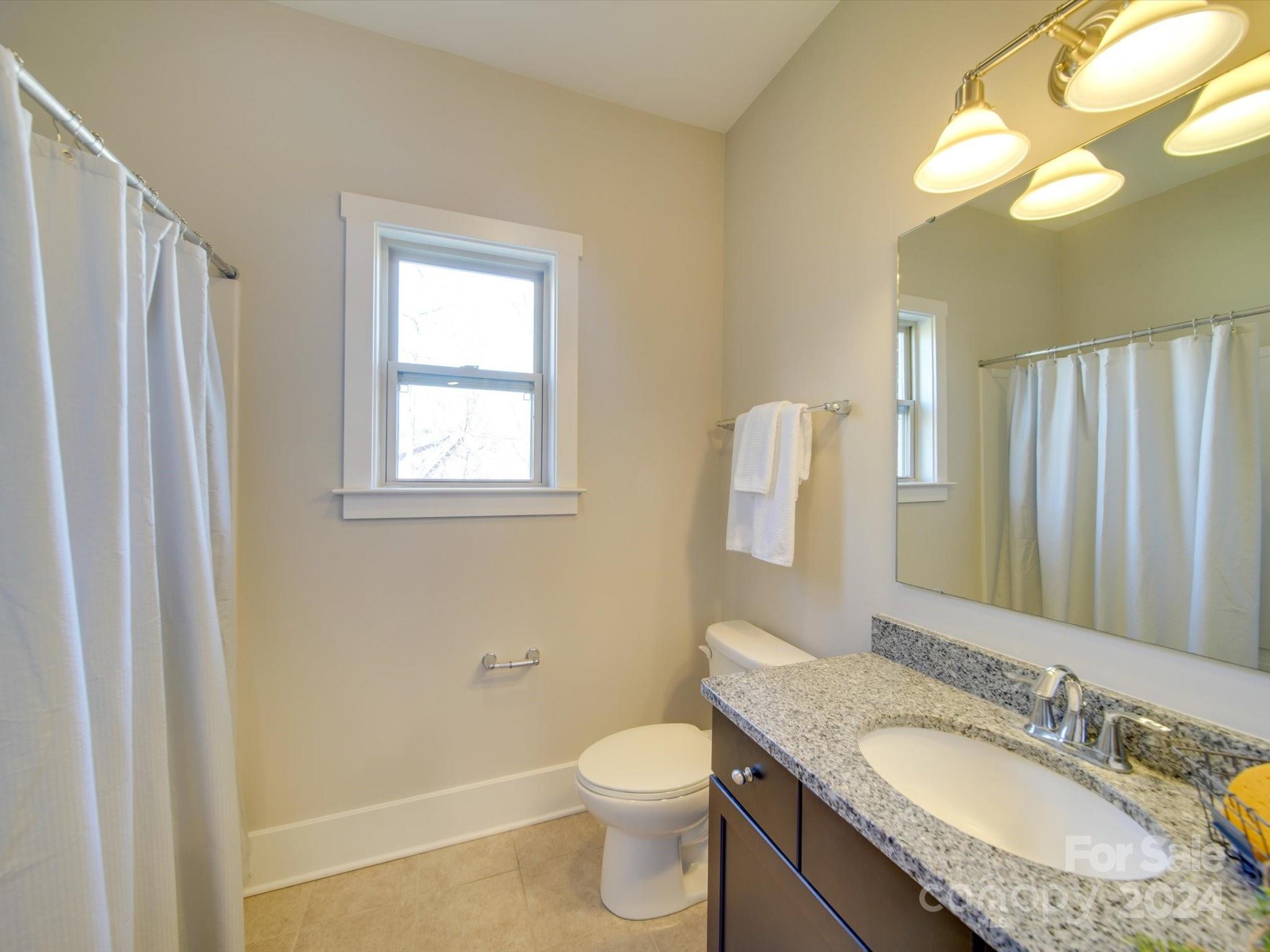 6723 Eliah Drive Weddington, NC 28104 - Photo 36 of 48 a bathroom with a granite countertop toilet a sink and a mirror