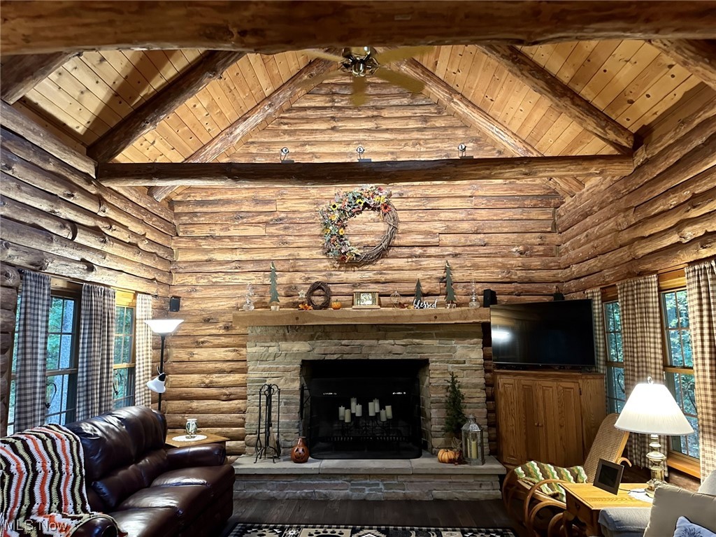 18072 Owen Road Middlefield, OH 44062 - Photo 5 of 13 Hardwood floored living room featuring log walls, a wealth of natural light, vaulted ceiling high, and a stone fireplace