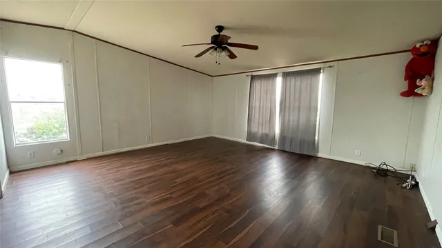an empty room with wooden floor chandelier fan and windows