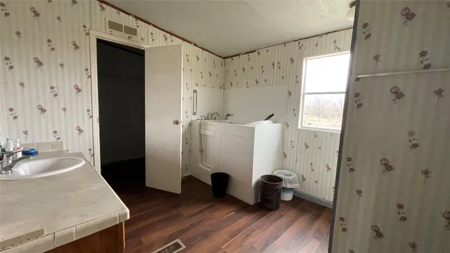 a bathroom with a tub shower sink and mirror