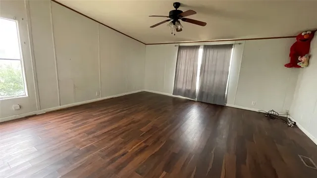 an empty room with wooden floor fan and windows