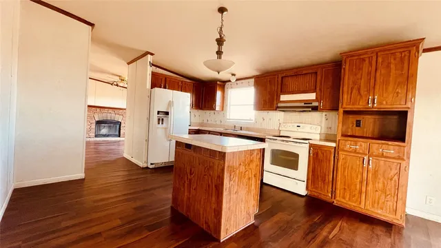 a kitchen with stainless steel appliances granite countertop a refrigerator a stove top oven a sink dishwasher and wooden floor