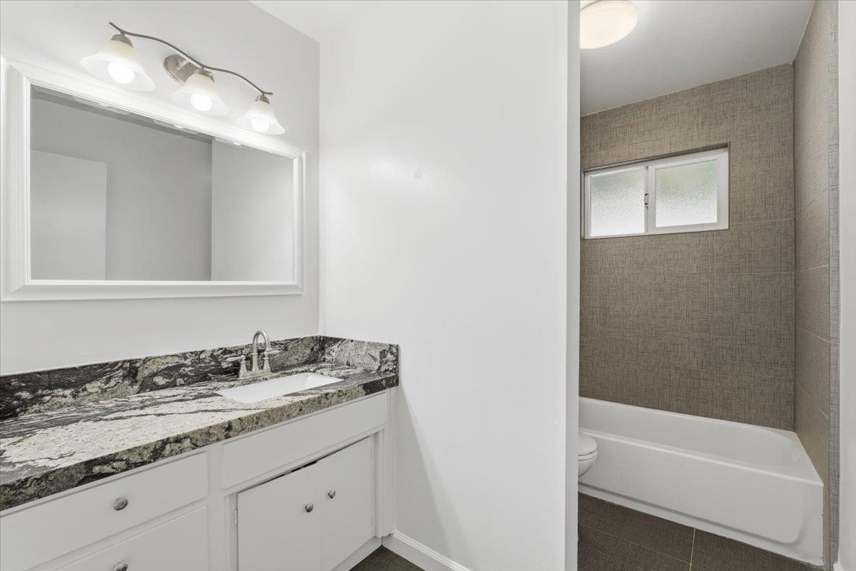 209 Tokay Avenue Modesto, CA 95350 - Photo 18 of 30 a bathroom with a granite countertop sink and a mirror