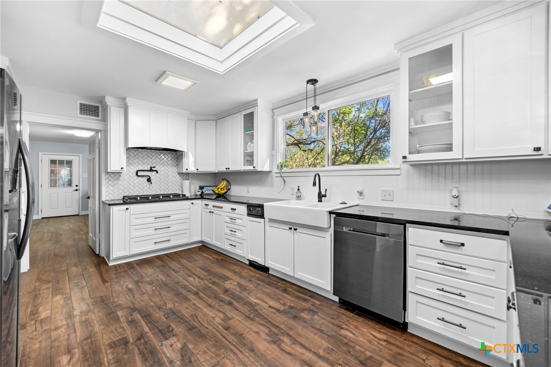 2509 Forest Trail Temple, TX 76502 - Photo 8 of 42 a kitchen with stainless steel appliances granite countertop a stove a sink and white cabinets with wooden floor