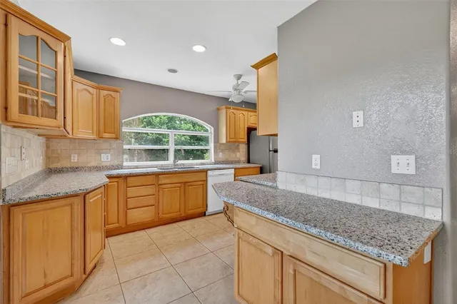 a kitchen with stainless steel appliances granite countertop a refrigerator a sink and white cabinets