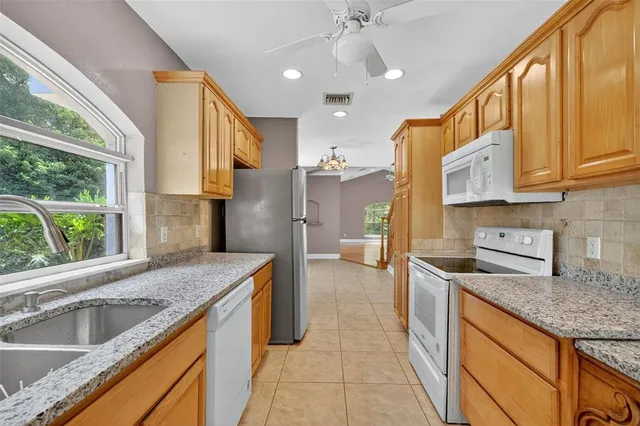 an empty room with wooden floor a ceiling fan and windows